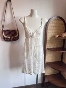 Close-up view of a white lace slip dress, featuring delicate floral embroidery and details.