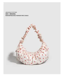 Close-up detail shot of a stylish gathered dumpling bag with red polka dots and ruffled handle.