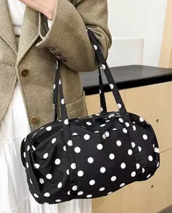 Close-up view of a black nylon polka dot tote bag, showing fabric texture and design details.