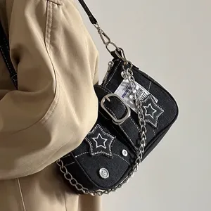 Detailed shot of black denim shoulder bag with white star embroidery and metal chain strap.