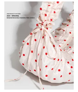 Close-up of ruched polka dot shoulder bag featuring cute red dots and drawstring details.