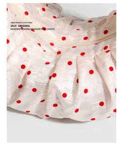 Detailed shot of trendy pleated polka dot dumpling bag with zipper and cute red dots.