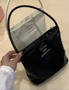 Detailed view of women fashion leather underarm shoulder handbag with embroidered letter text.