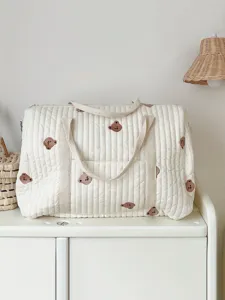 Detailed view of the quilted white mommy bag with cute bear embroidery, soft fabric and fine stitching.