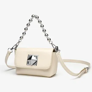 Close-up of elegant cream white crossbody bag with metal bead handle and chic pyramid clasp.