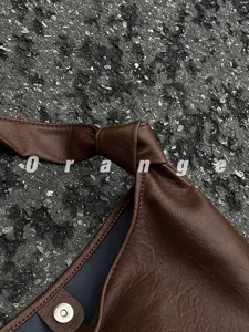 Brown leather shoulder bag detail, stylish knotted strap and magnetic snap closure.