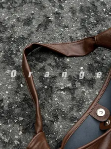 Close-up detail of brown leather shoulder bag strap and snap button for daily casual use.