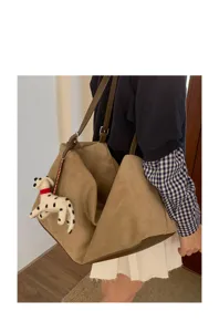 Detailed view of the casual brown suede shoulder pillow bag with cute plush puppy keychain.