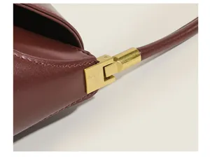 Close-up detail of women's vintage underarm bag, wine red leather with retro gold hardware hinge.