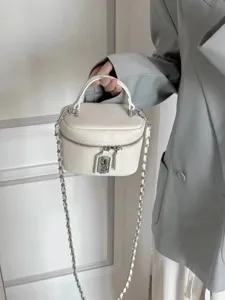 Detail shot of a white leather box bag with silver chain strap and metal lock closure.