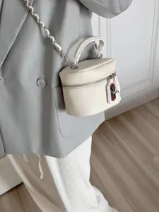 Detailed view of white textured leather vanity box bag with chain strap and top handle.