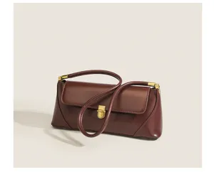 Detail view of a retro brown leather underarm baguette bag with chic gold hardware.