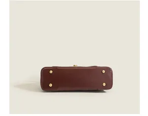 Detailed view of the bottom bag with gold metal feet, showing fine leather texture and hardware.