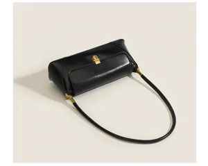 Minimalist black leather underarm bag detail, featuring retro gold hardware and a slim strap.