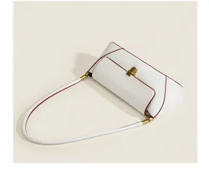 White vintage baguette shoulder bag detail, elegant red piping and gold lock hardware.