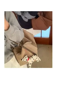 Detailed view of casual suede shoulder pillow bag featuring cute puppy pendant and soft texture.