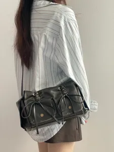 Details of black distressed multi-pocket shoulder bag with bow drawstrings and metal snaps.