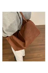 Detail view of the brown faux suede slouchy shoulder bag worn casually, showing its soft texture.