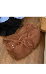 Brown suede shoulder bag detail showing soft texture, slim strap and metal buckle, stylish.