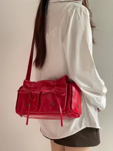 Detail view of red glossy bow crossbody bag with ruffles and multiple pockets for women style.
