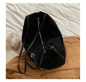 Detail view of the black suede backpack featuring center zipper and slim straps on chic bed setup.
