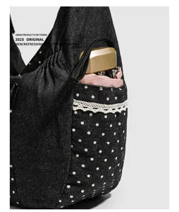 Primo piano dettagliato di borsa tote in denim nero con pois bianchi e tasca in pizzo delicato.