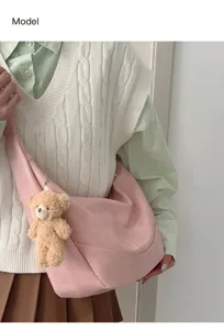 Detailed view of the soft pink slouchy crossbody dumpling bag featuring a cute plush bear pendant.
