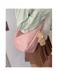 Pink slouchy dumpling shoulder bag detail showcasing soft leather texture and bear charm.