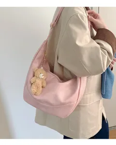 Pink slouchy hobo shoulder bag detail shot, soft material with cute teddy bear charm.