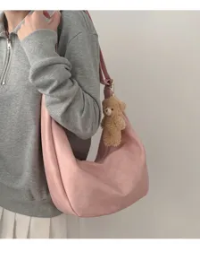 Detailed shot of a soft pink slouchy dumpling bag featuring a cute bear pendant.