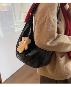 Detailed view of a soft black leather hobo dumpling bag featuring a cute plush bear pendant.