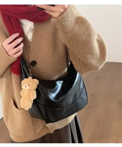 Detail view of black soft leather hobo crossbody bag featuring fluffy bear pendant.