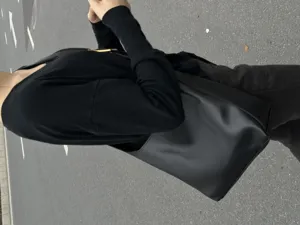 Black slouchy faux leather shoulder bag worn outdoors, soft daily casual tote design detail.