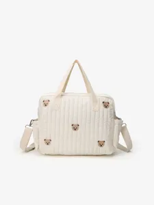 Detailed view of the white quilted diaper bag featuring cute bear embroidery and handles.