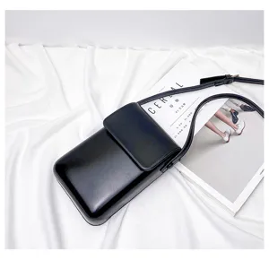 Detail view of the black mini crossbody phone bag on draped white fabric with prop.