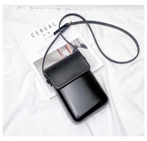 Detail view of a minimalist black mini crossbody phone bag on white fabric background.