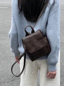 Vista di dettaglio del mini zaino marrone rétro indossato sulla schiena, accessorio moda.