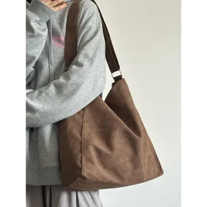 Detailed view of a stylish brown hobo shoulder bag worn with a casual grey hoodie outfit.