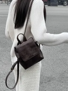 Dettaglio di uno zainetto retro marrone elegante indossato in strada, stile unico e chic.