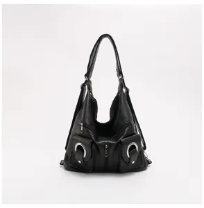 Dettaglio borsa multifunzione in morbida pelle nera, design tasche con anelli metallici.
