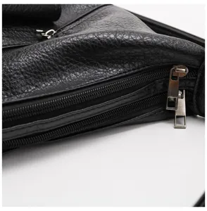 Primo piano dettaglio di borsa in vera pelle morbida nera con cerniere metalliche.