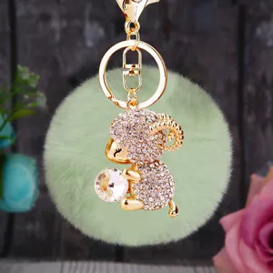 Fluffy green pom pom keychain with sparkling rhinestone ram holding crystal charm metal ring.