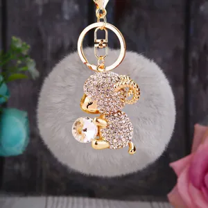 Plush sheep keychain detail showing sparkling rhinestones and fluffy gray pom pom design.
