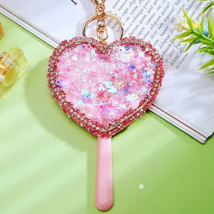 Cute heart-shaped quicksand mirror keychain with rhinestones and pink handle for bags and keys.
