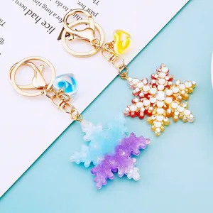 Detail shot of colorful gradient rhinestone snowflake keychain with gold metal ring and charm.