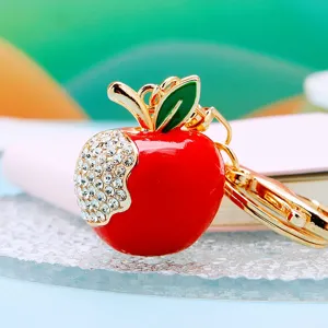 Close-up of cute rhinestone apple keychain pendant, sparkling crystal details and enamel finish.