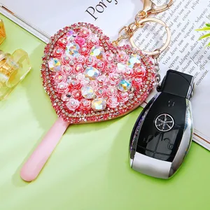 Close-up detail of the rhinestone heart mirror keychain with pink roses and luxury car key pendant.