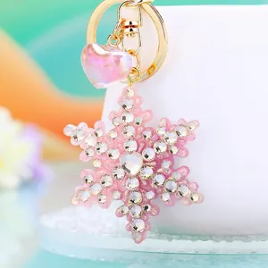 Closeup detail view of the pink rhinestone snowflake keychain with gold ring and iridescent heart pendant.