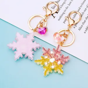 Close-up detail of sparkling rhinestone snowflake keychain with gradient heart pendant and hook.
