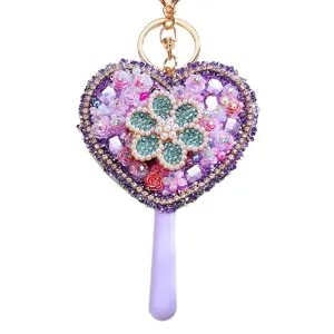 Closeup detail of the sparkling rhinestone heart mirror keychain with purple handle and gold ring.